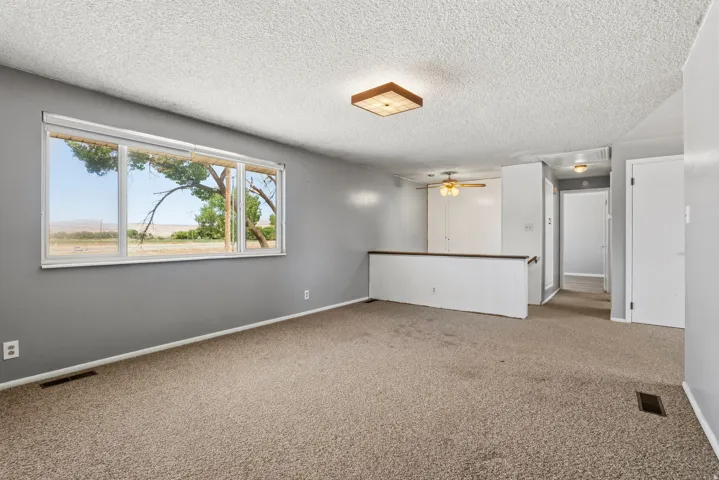 Carpeted living space featuring a large picture window, painted interior walls, and textured ceilings