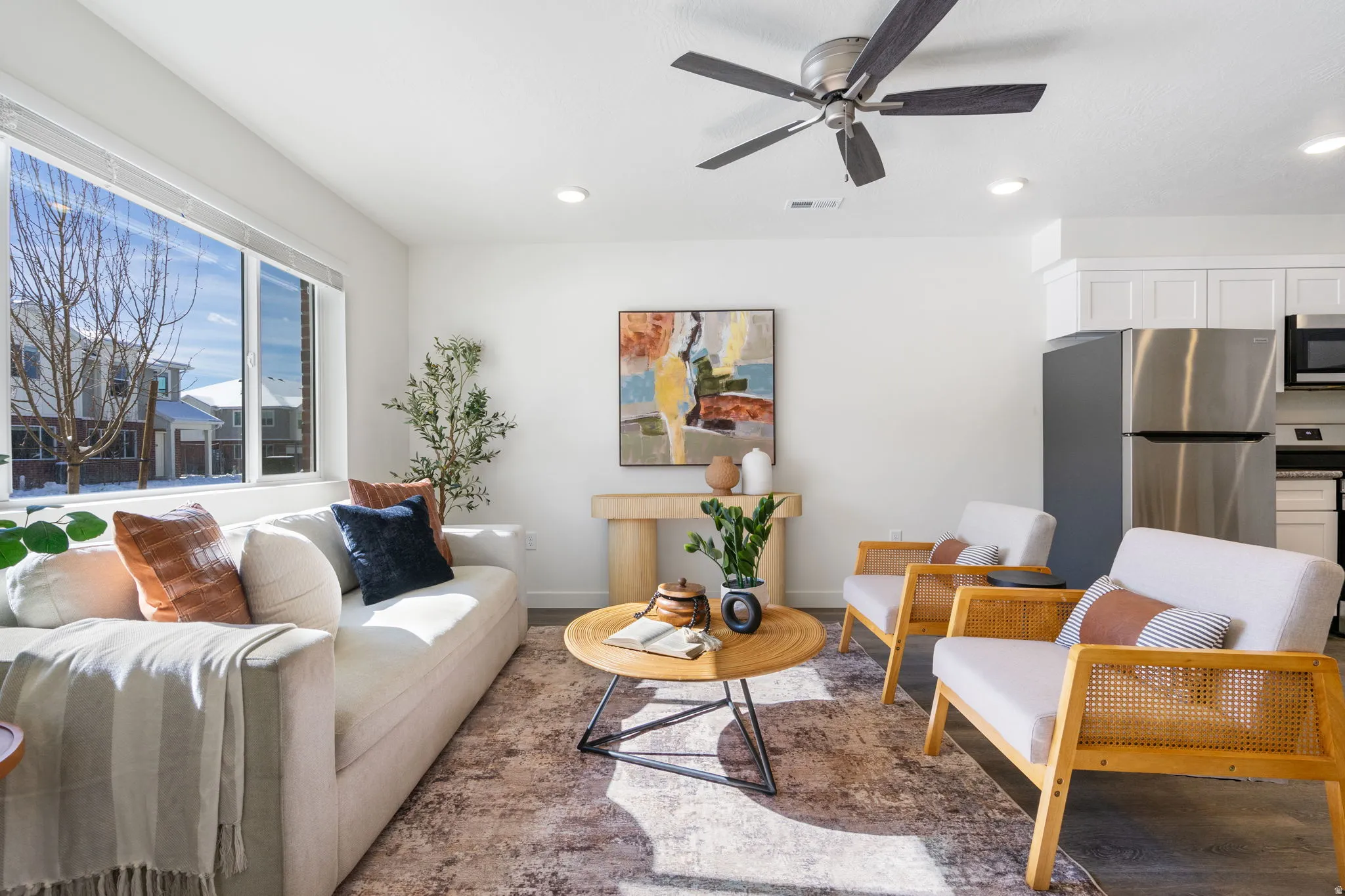 Bright open-concept living area featuring a large window, recessed lighting, and a ceiling fan