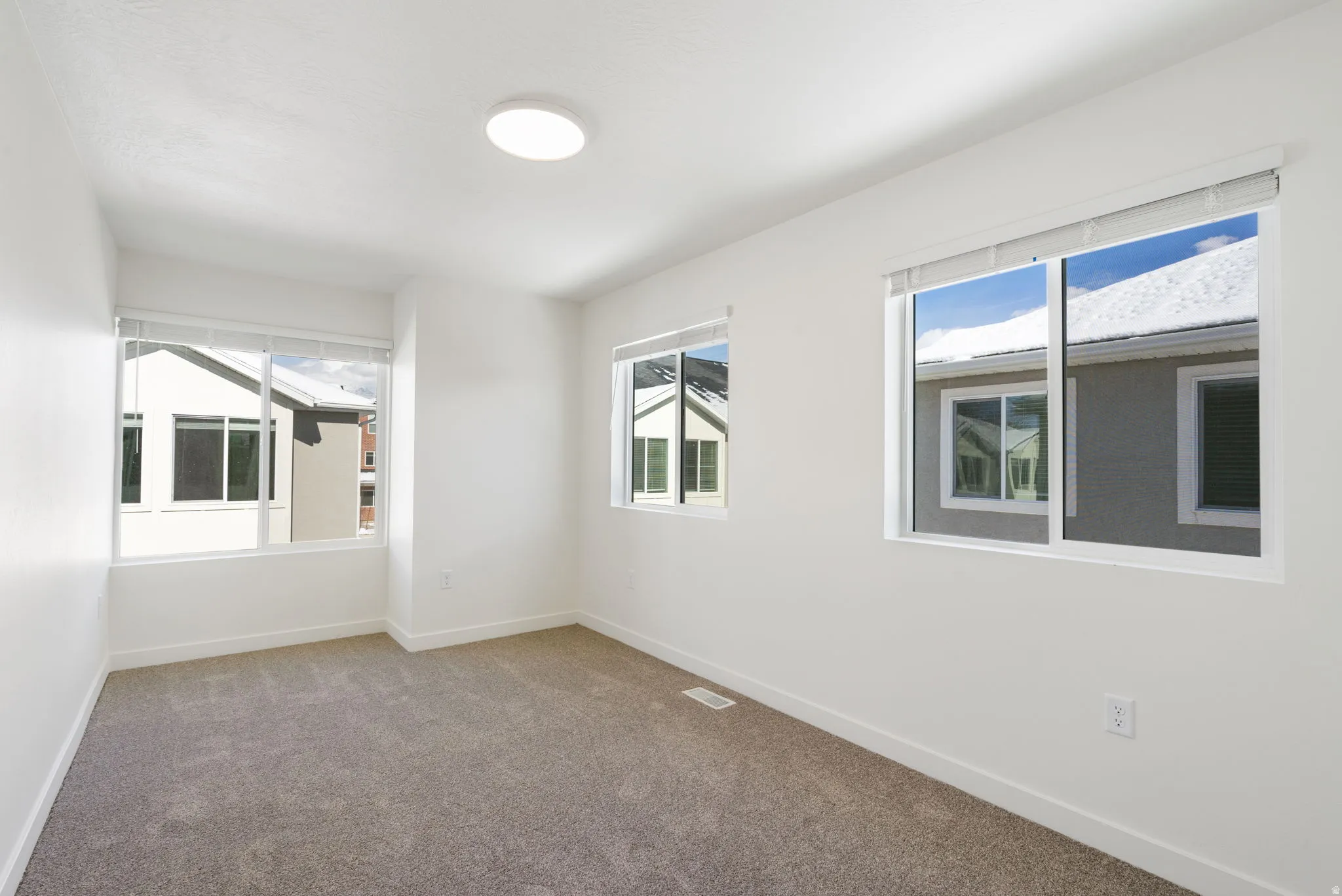 Bright room featuring neutral carpet flooring, white walls, and a modern flush-mount ceiling light