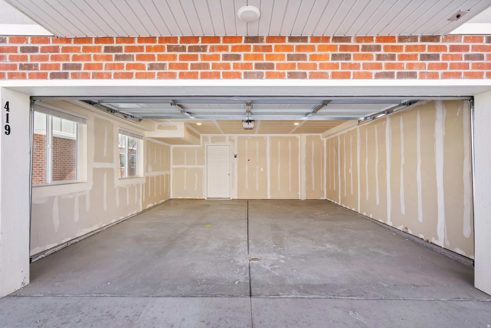 Spacious garage featuring a concrete floor, two windows providing natural light, and an interior access door