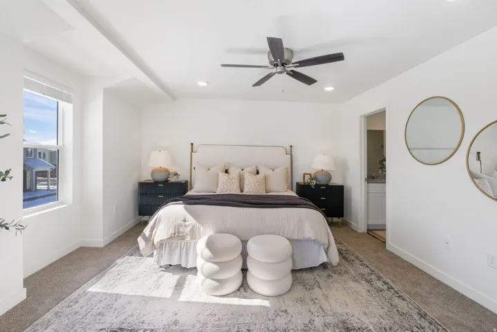 Spacious bedroom with light-colored carpeting, a large window, a ceiling fan, and recessed lighting