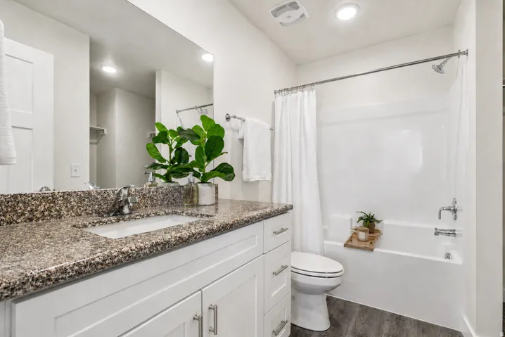 Bathroom featuring a spacious vanity with granite-style countertop, undermount sink, and polished chrome fixtures