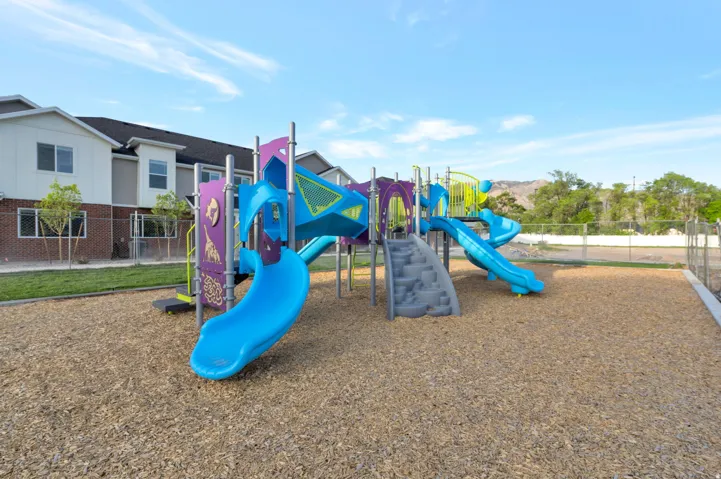 Outdoor play structure featuring multiple slides, climbing elements, and colorful platforms
