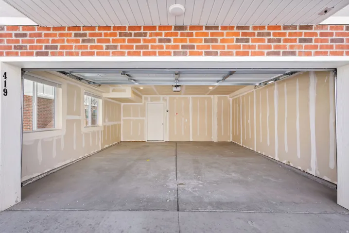 Spacious garage featuring a concrete floor, two windows providing natural light, and an interior access door