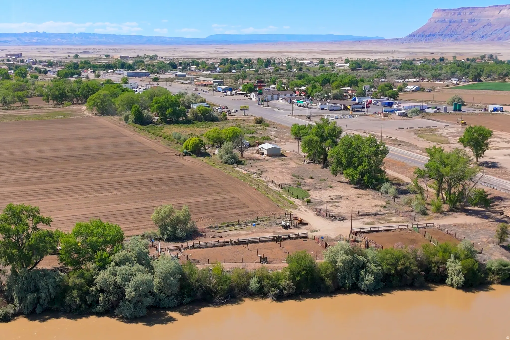 Expansive property featuring tilled agricultural land, a river frontage, and a distant town center