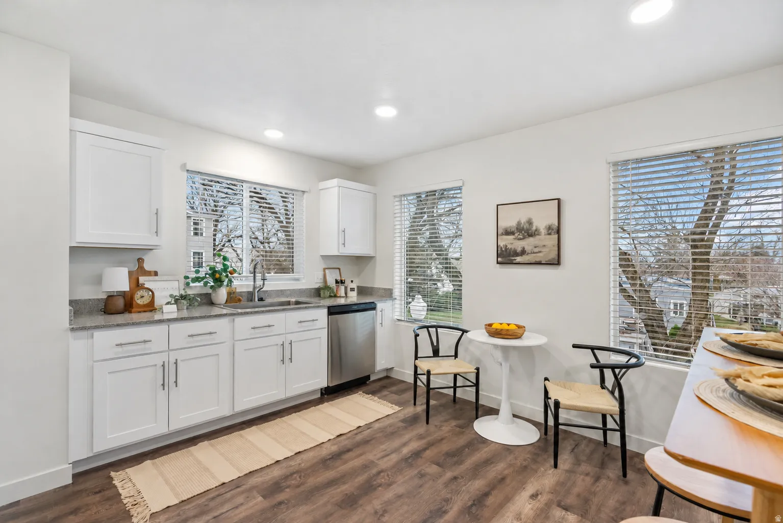 Kitchen featuring white cabinetry, light-toned countertops, stainless steel appliances, and wood-finish flooring