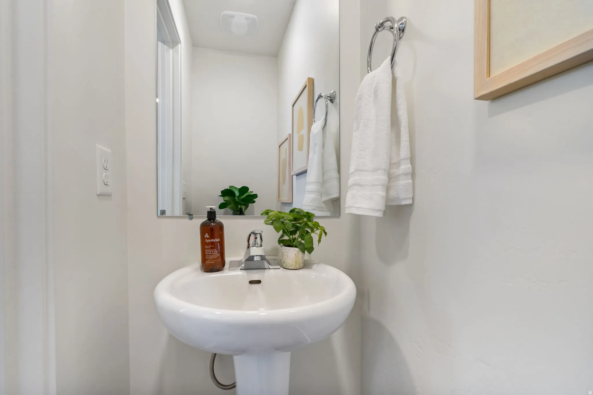 Pedestal sink with chrome faucet, mirror, and recessed ceiling lighting