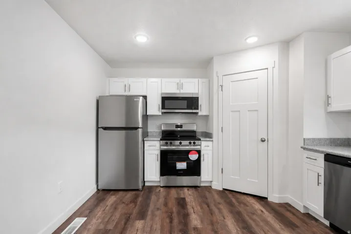 Kitchen featuring wood-finish flooring, white shaker cabinetry, stainless steel appliances, and a light-colored countertop