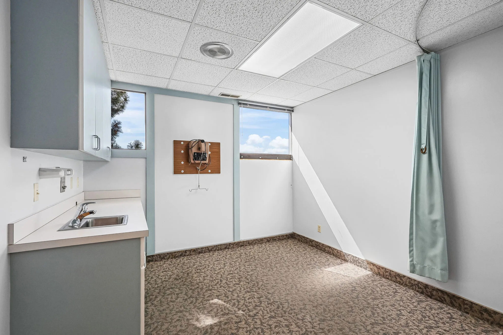 Room featuring a drop ceiling with recessed lighting, patterned carpet flooring, and white walls