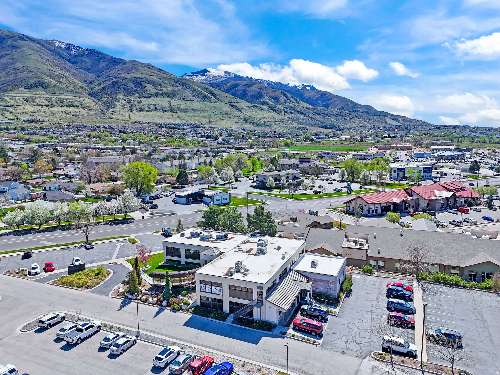 Office building with ample parking, surrounded by mature landscaping and a mountainous backdrop