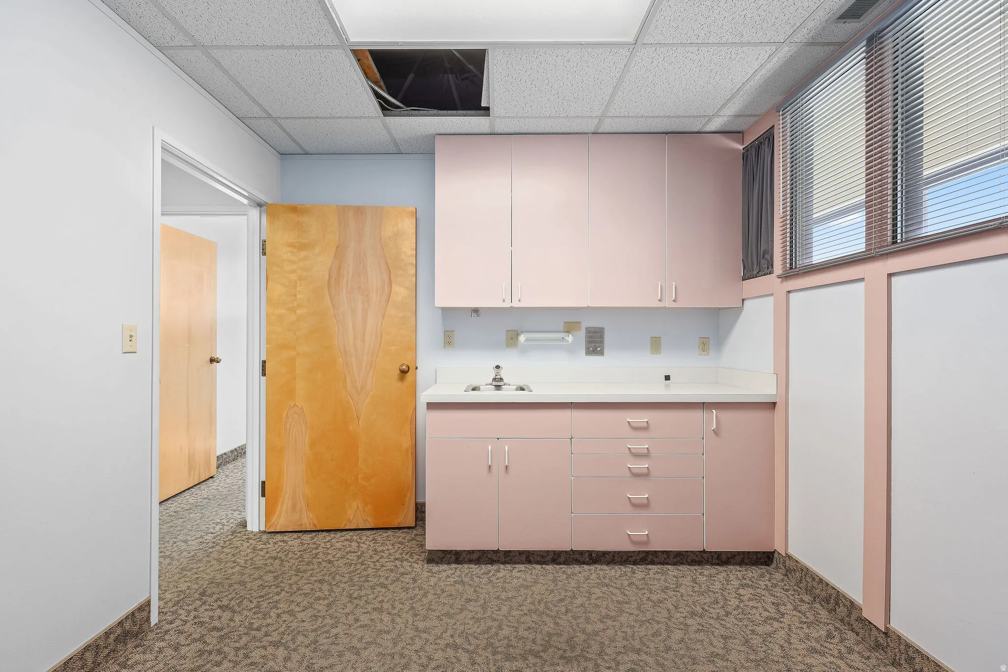 Built-in cabinetry with pink finishes, white countertops, and a stainless steel sink