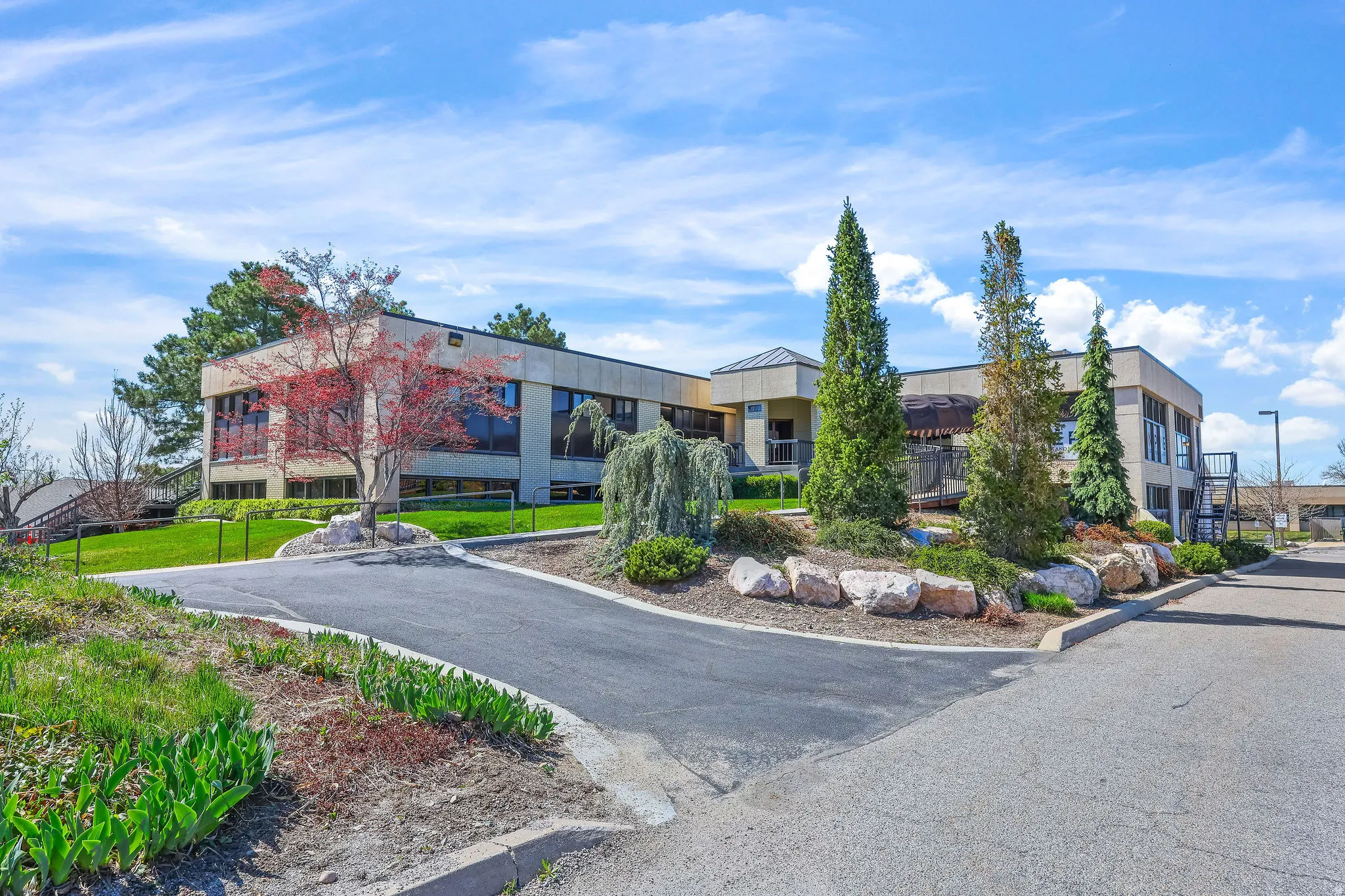 Contemporary building exterior featuring large windows and a paved driveway