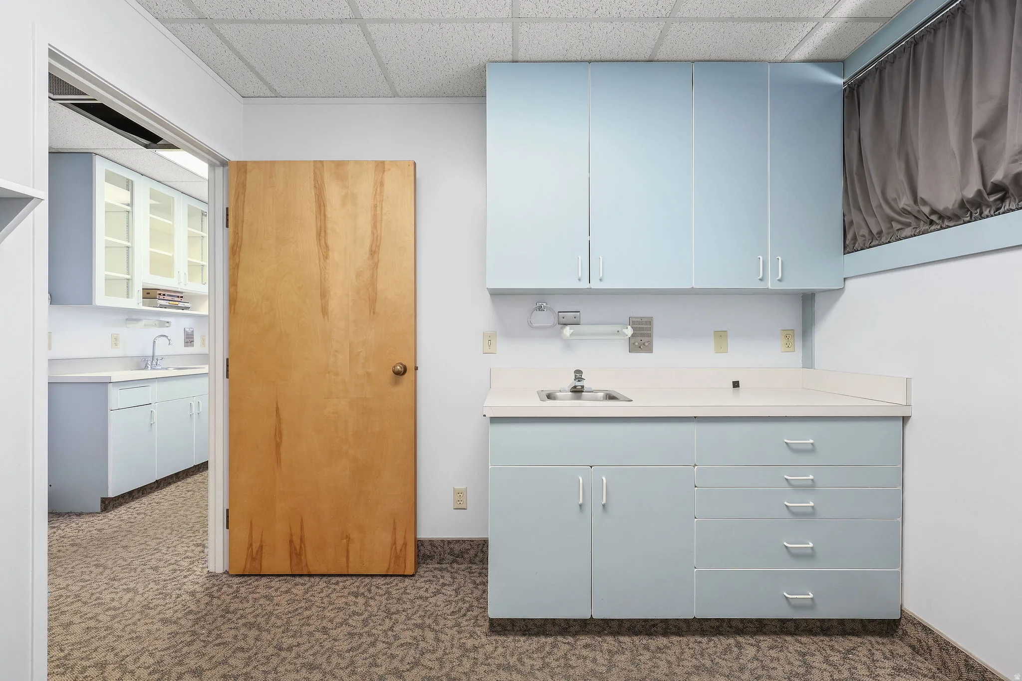 Workspace featuring light blue cabinetry, built-in sink, and white countertops