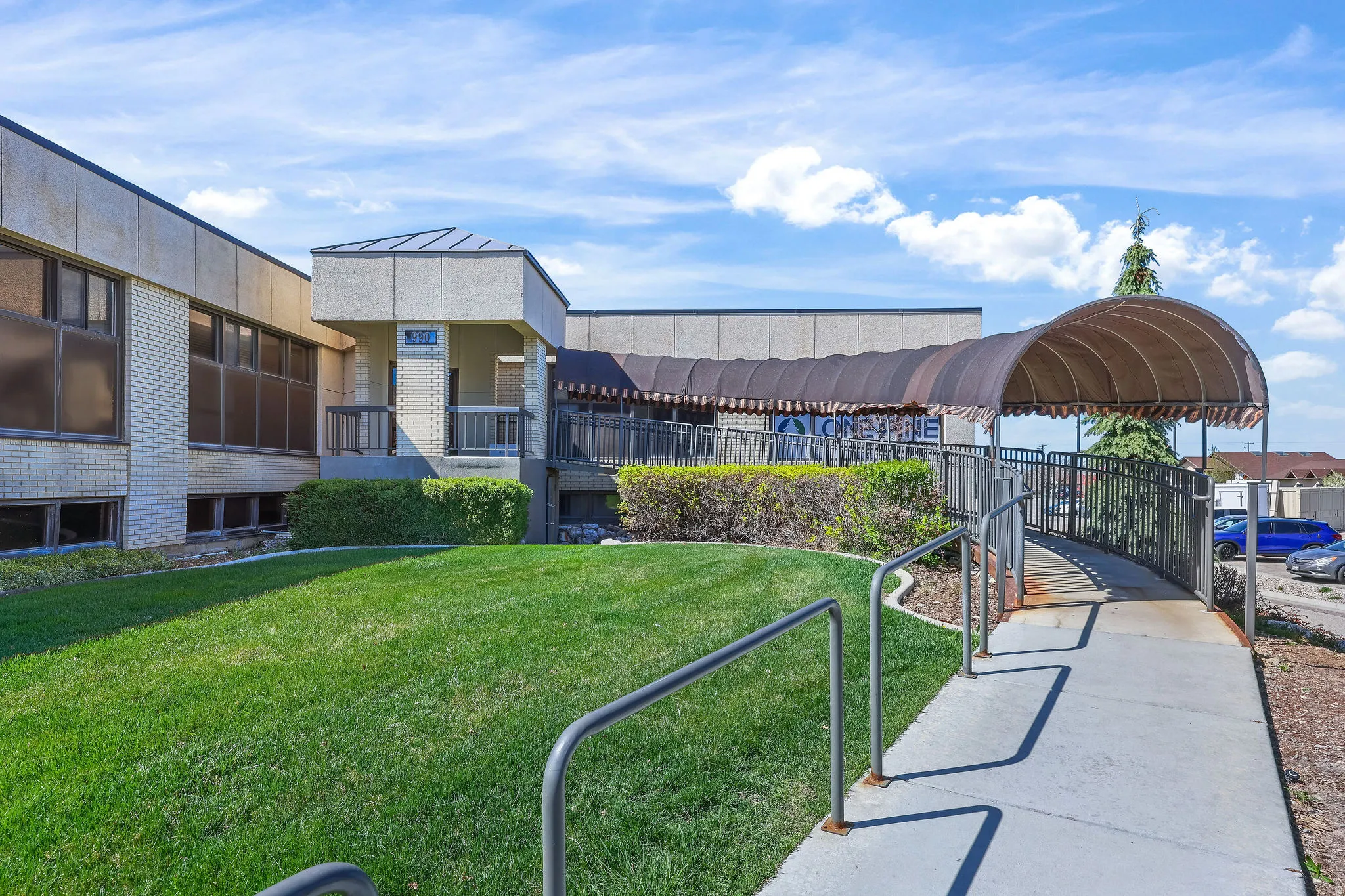 Commercial building exterior featuring a covered entry ramp and a manicured lawn