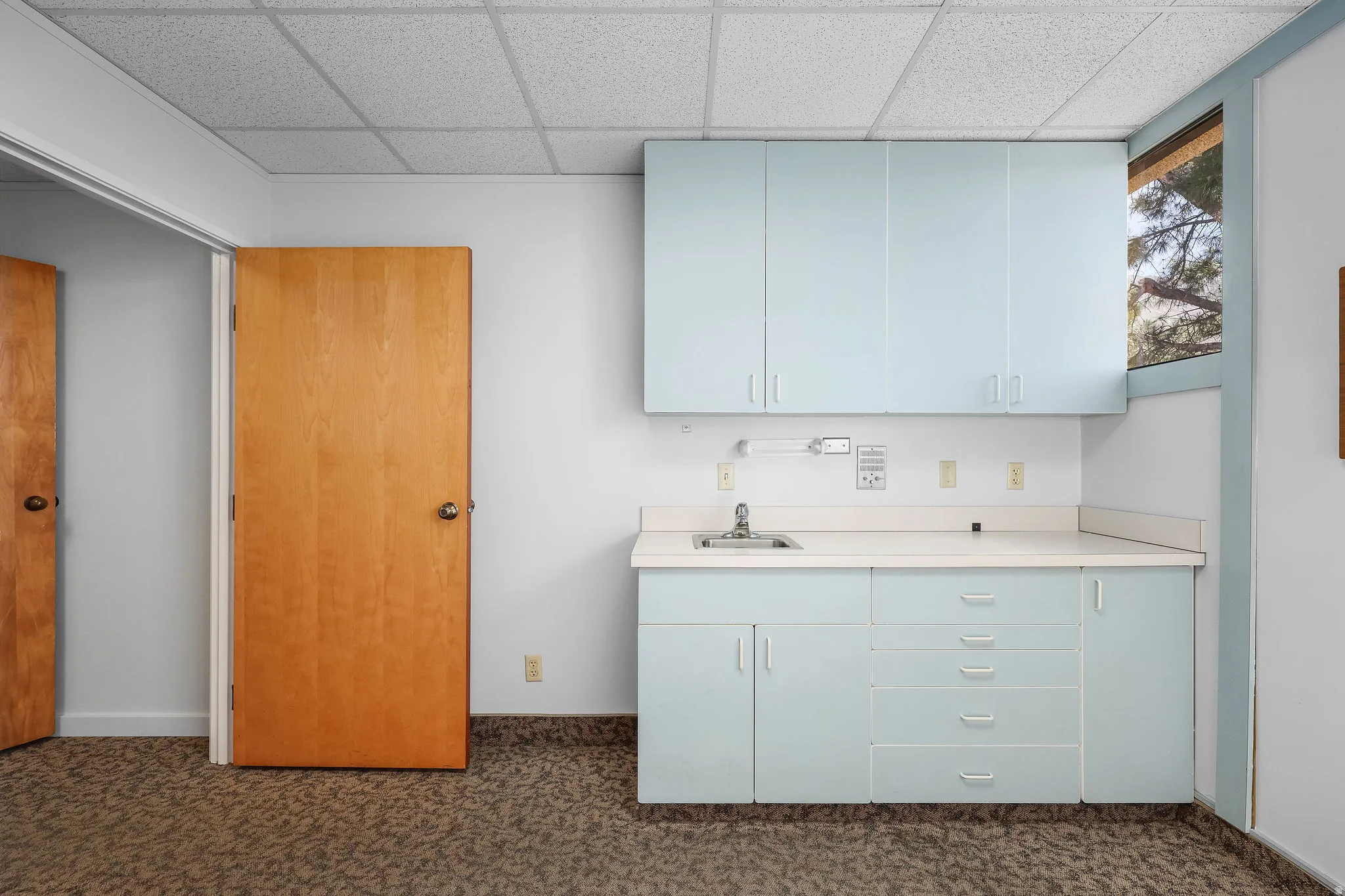Utility sink with light blue cabinetry, white countertop, and upper storage