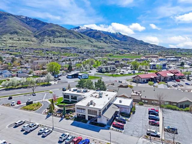 Office building with ample parking, surrounded by mature landscaping and a mountainous backdrop