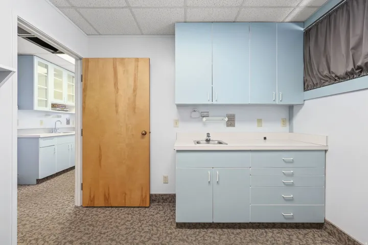 Workspace featuring light blue cabinetry, built-in sink, and white countertops
