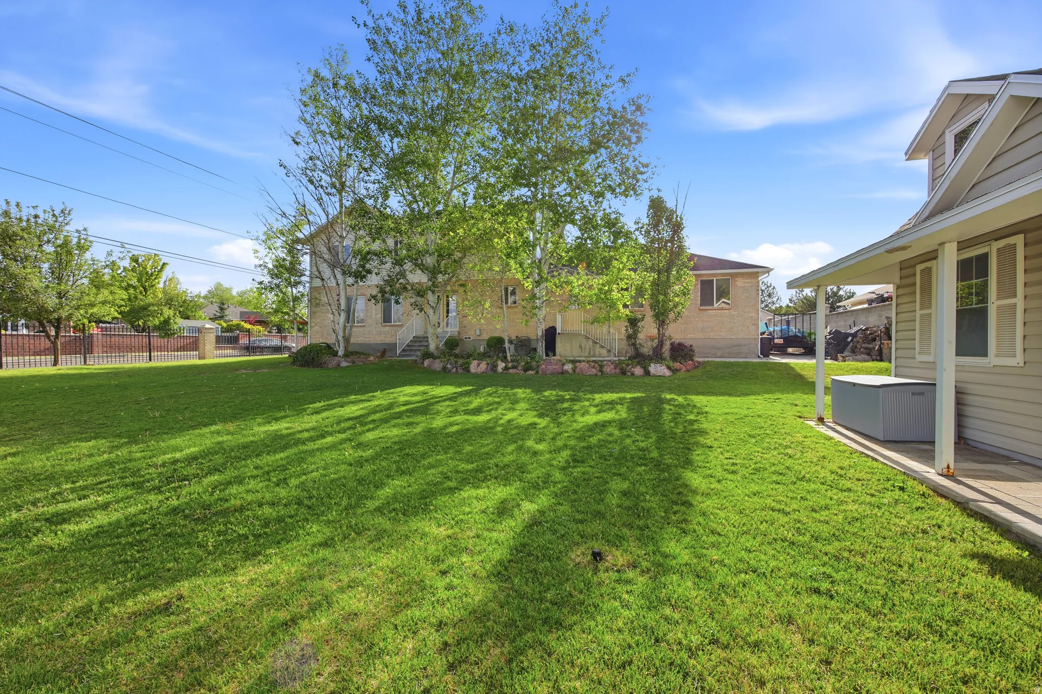 Expansive green lawn with mature trees and a fenced perimeter