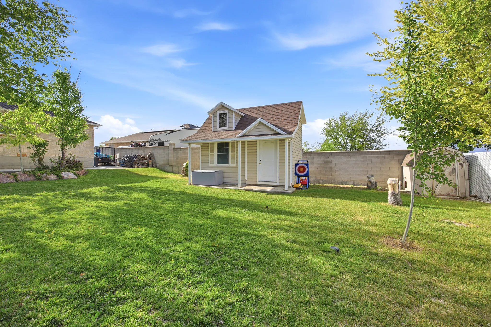 Expansive green lawn featuring a detached shed with a dormer window, siding exterior, and a covered porch