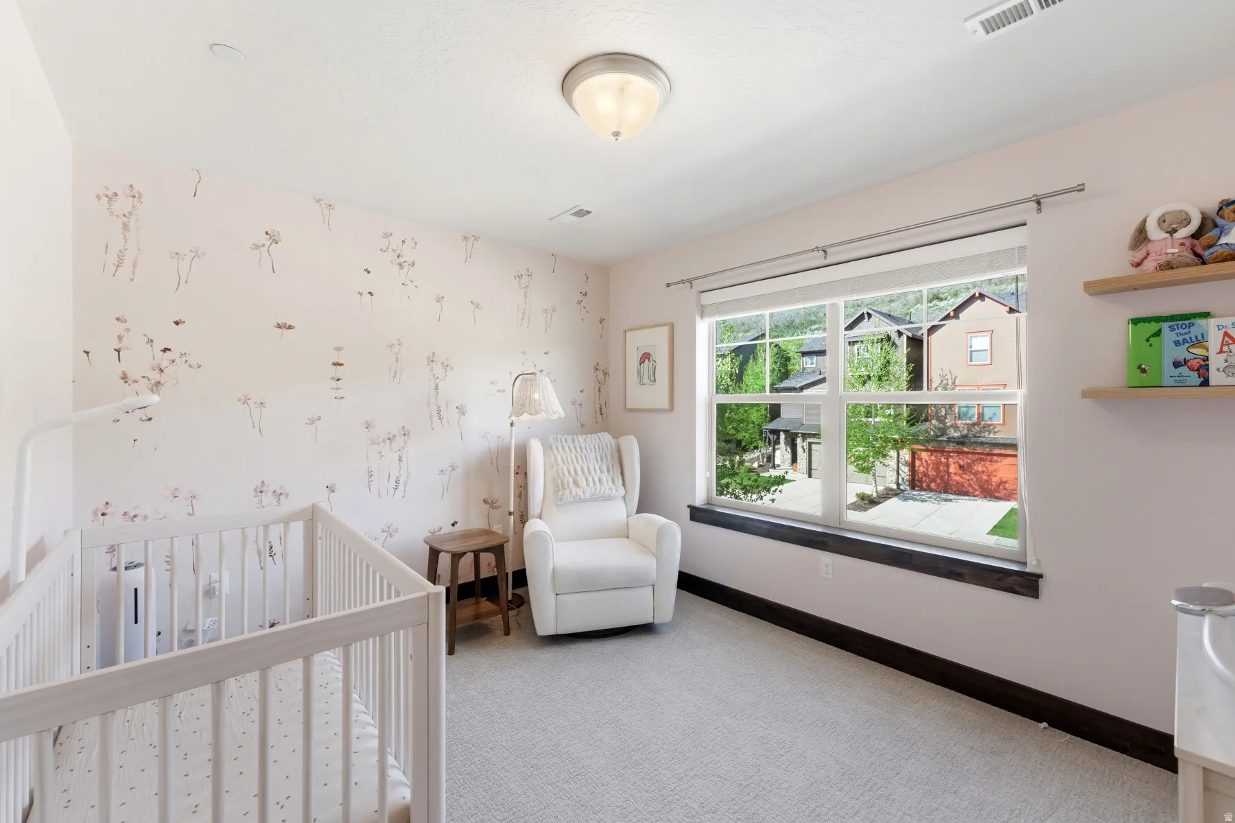 Bright room featuring light-toned carpeting, a large window with white framing, and a dark wood-finish sill