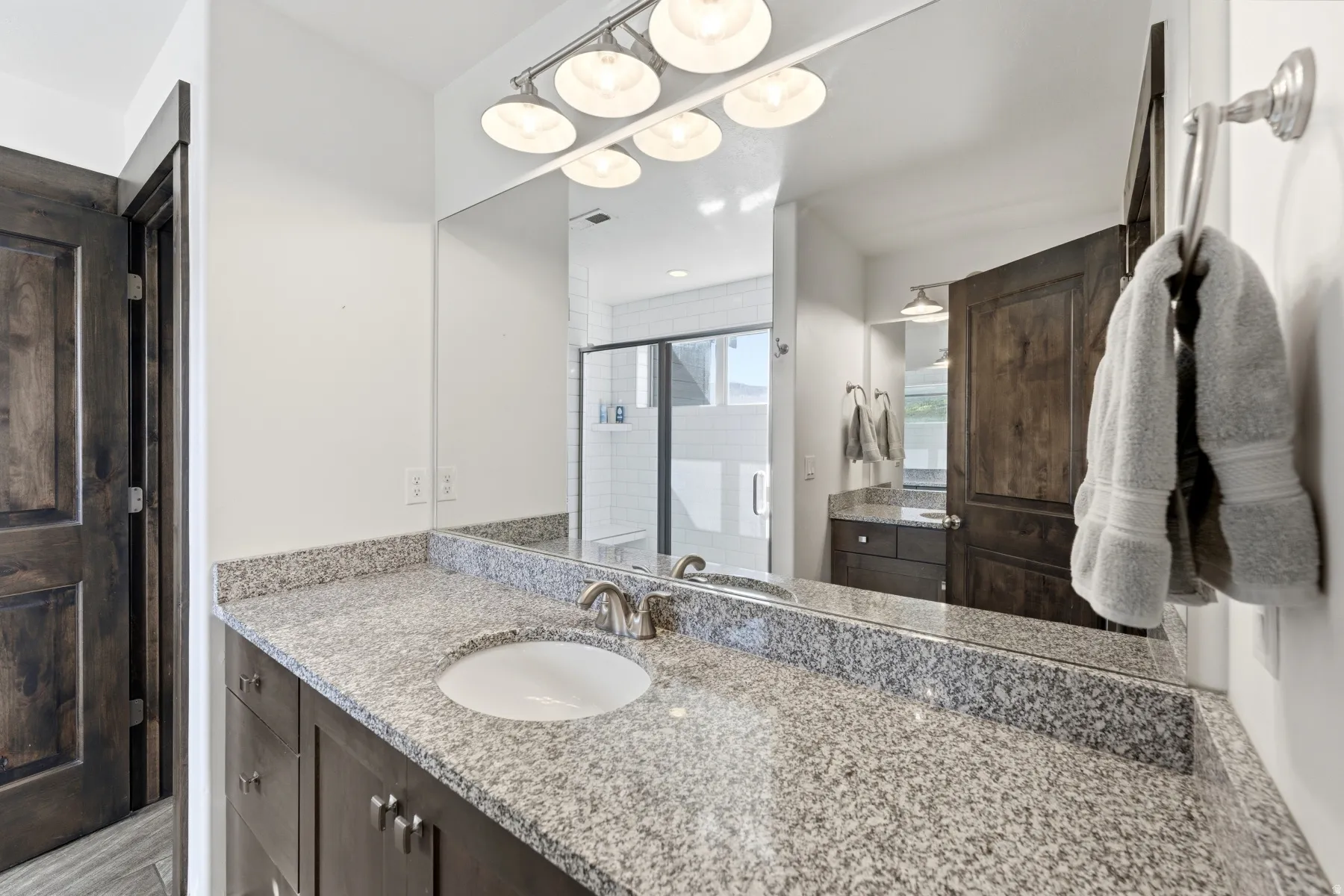 Bathroom vanity featuring a polished stone countertop with an undermount sink and brushed nickel faucet