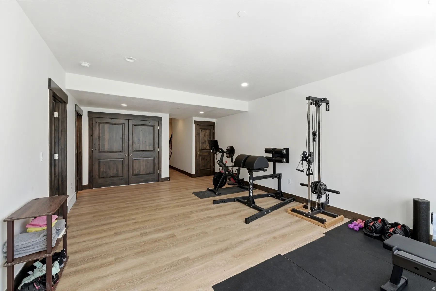 Versatile lower-level space featuring wood-finish flooring, recessed lighting, and dark wood trim