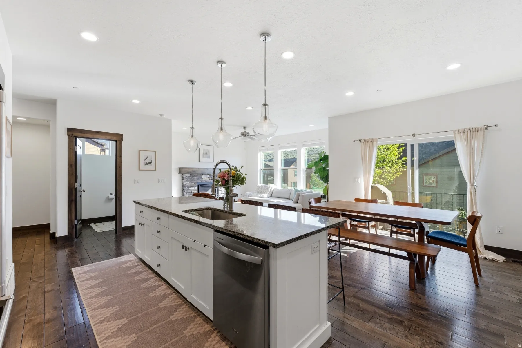 Spacious kitchen featuring a large island with a stainless steel sink and dishwasher, pendant lighting, recessed lighting, and rich wood-finish flooring