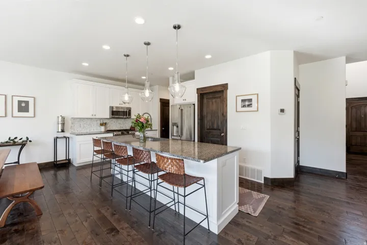Spacious kitchen featuring an expansive center island with seating, white cabinetry, granite countertops, and stainless steel appliances