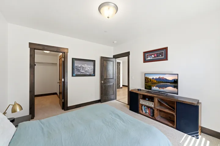 Carpeted bedroom featuring white walls, dark wood-finish trim, and a semi-flush mount ceiling light fixture