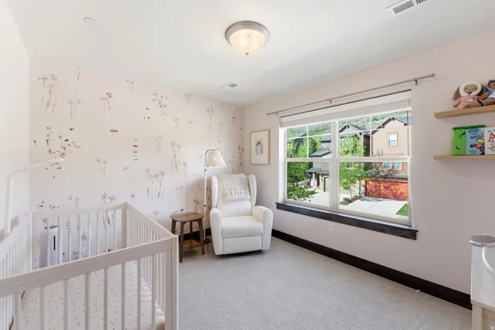 Bright room featuring light-toned carpeting, a large window with white framing, and a dark wood-finish sill