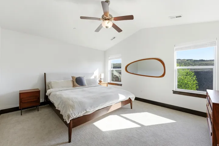 Vaulted ceiling bedroom with light-toned carpet flooring