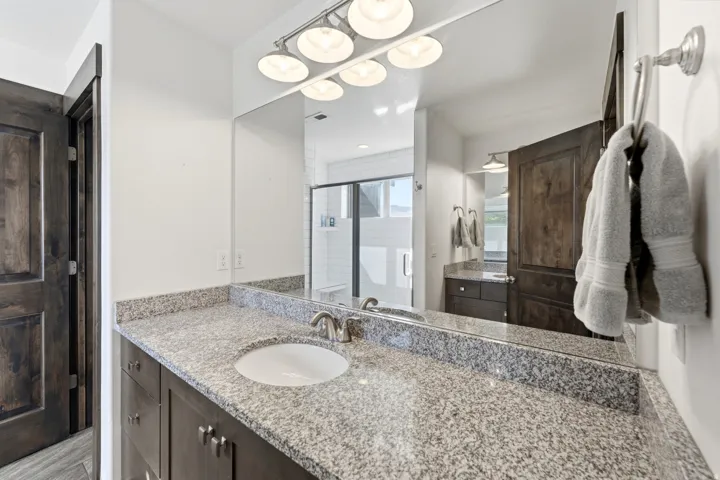 Bathroom vanity featuring a polished stone countertop with an undermount sink and brushed nickel faucet
