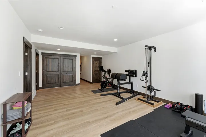Versatile lower-level space featuring wood-finish flooring, recessed lighting, and dark wood trim