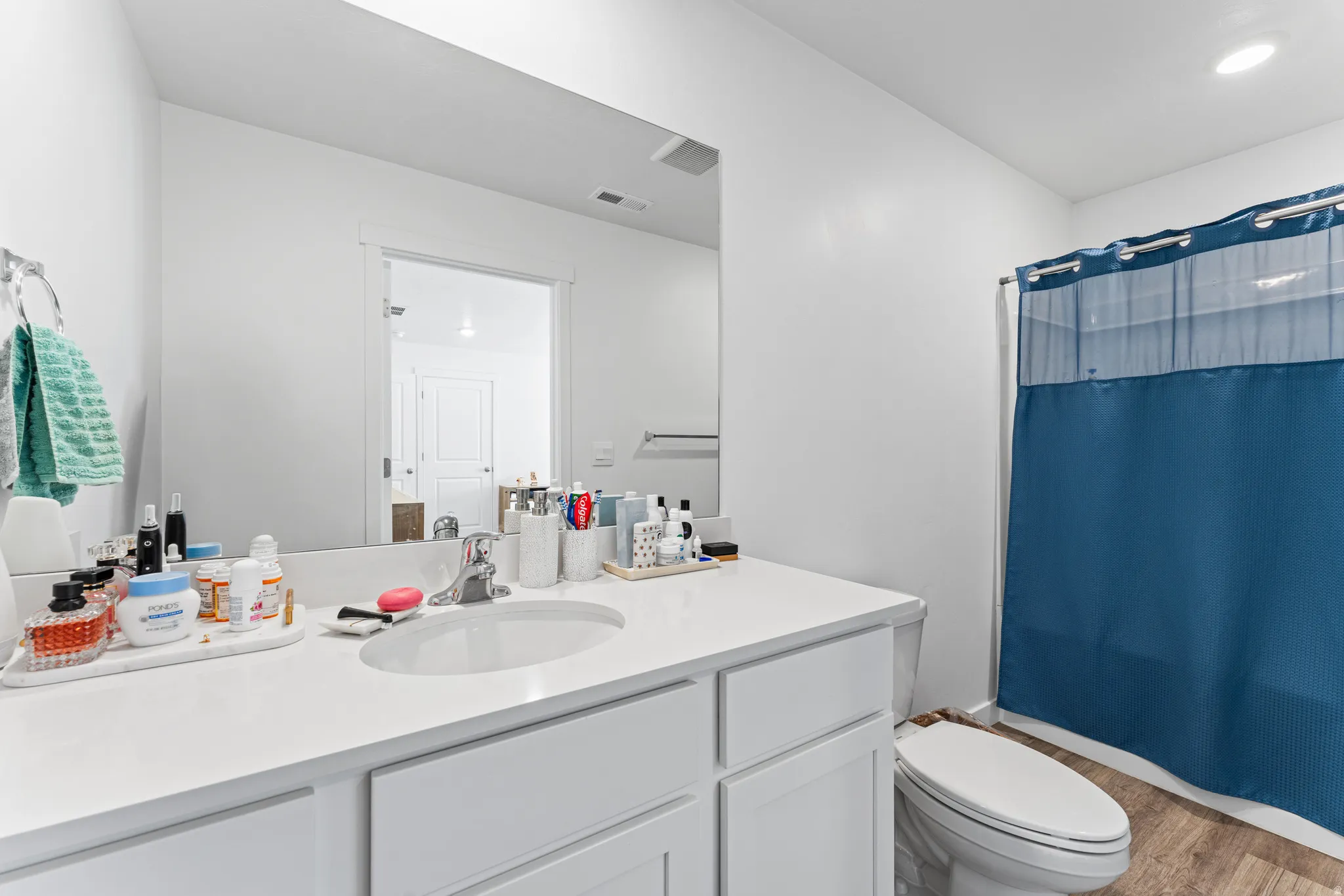 Bathroom featuring a white vanity with an integrated sink, polished chrome faucet, and expansive mirror
