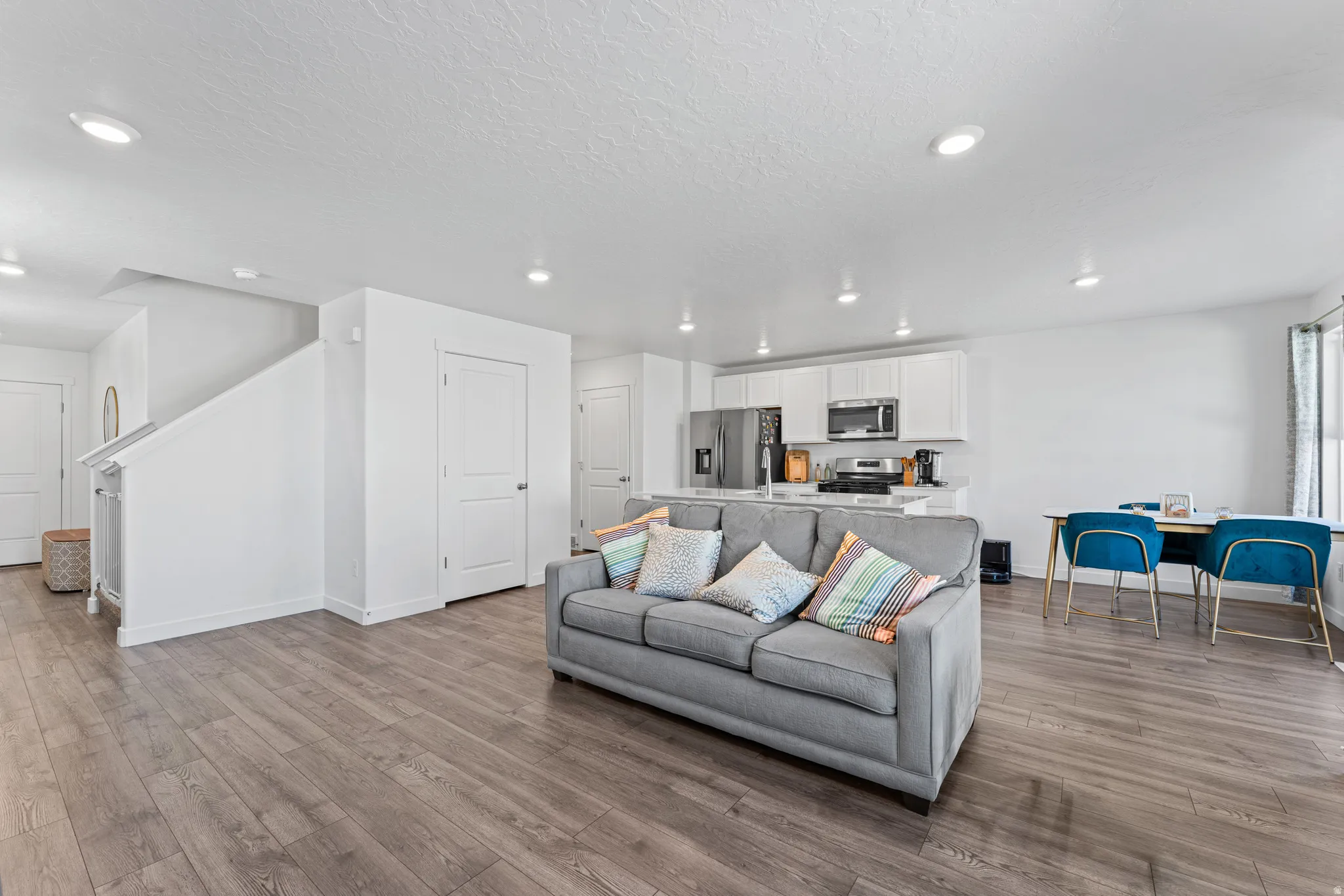 Open-concept living area featuring wood-finish flooring, recessed lighting, and a neutral color palette