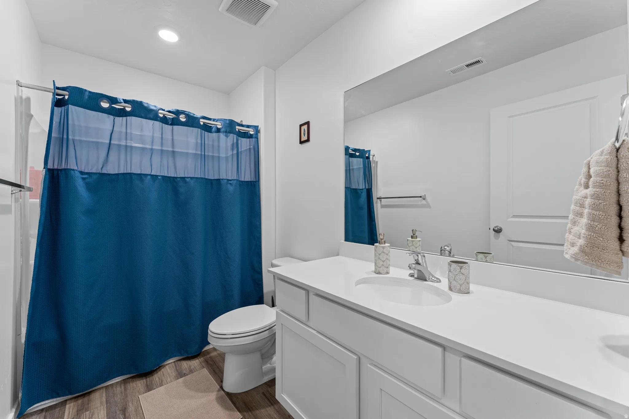 Bathroom featuring a spacious vanity with an integrated sink and large mirror