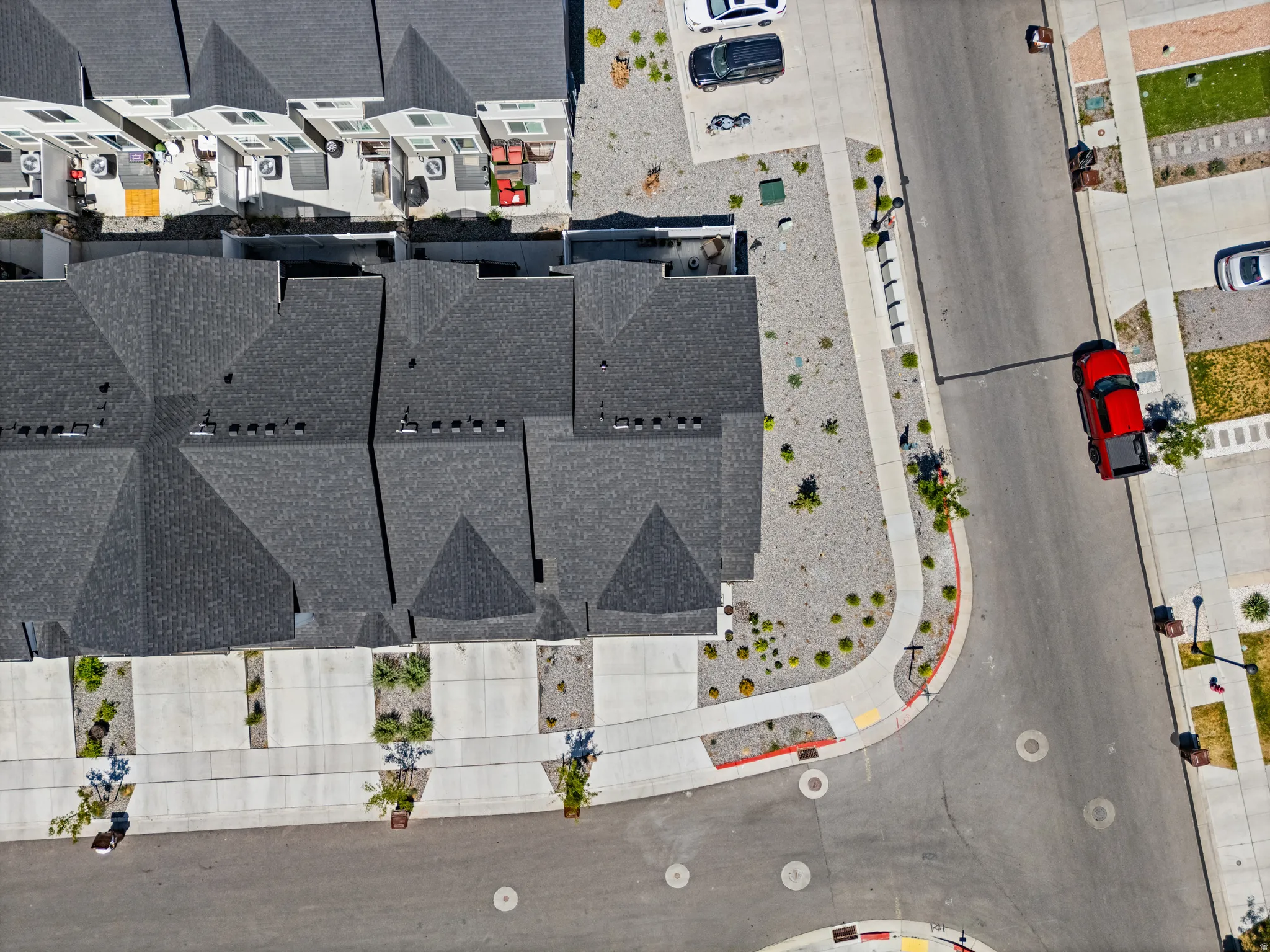 Aerial perspective showcasing a residential street with uniform asphalt paving and concrete sidewalks