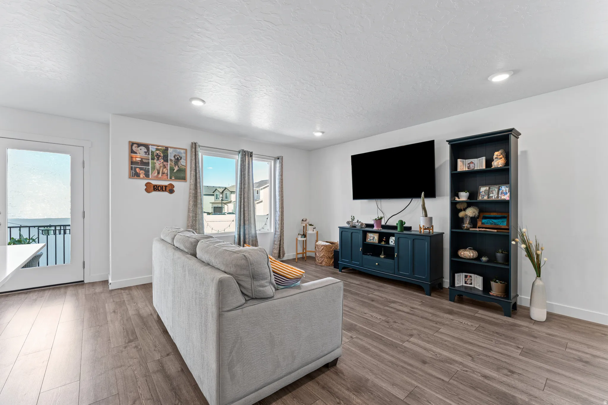 Living area featuring wood-finish flooring, white walls, recessed lighting, and multiple windows