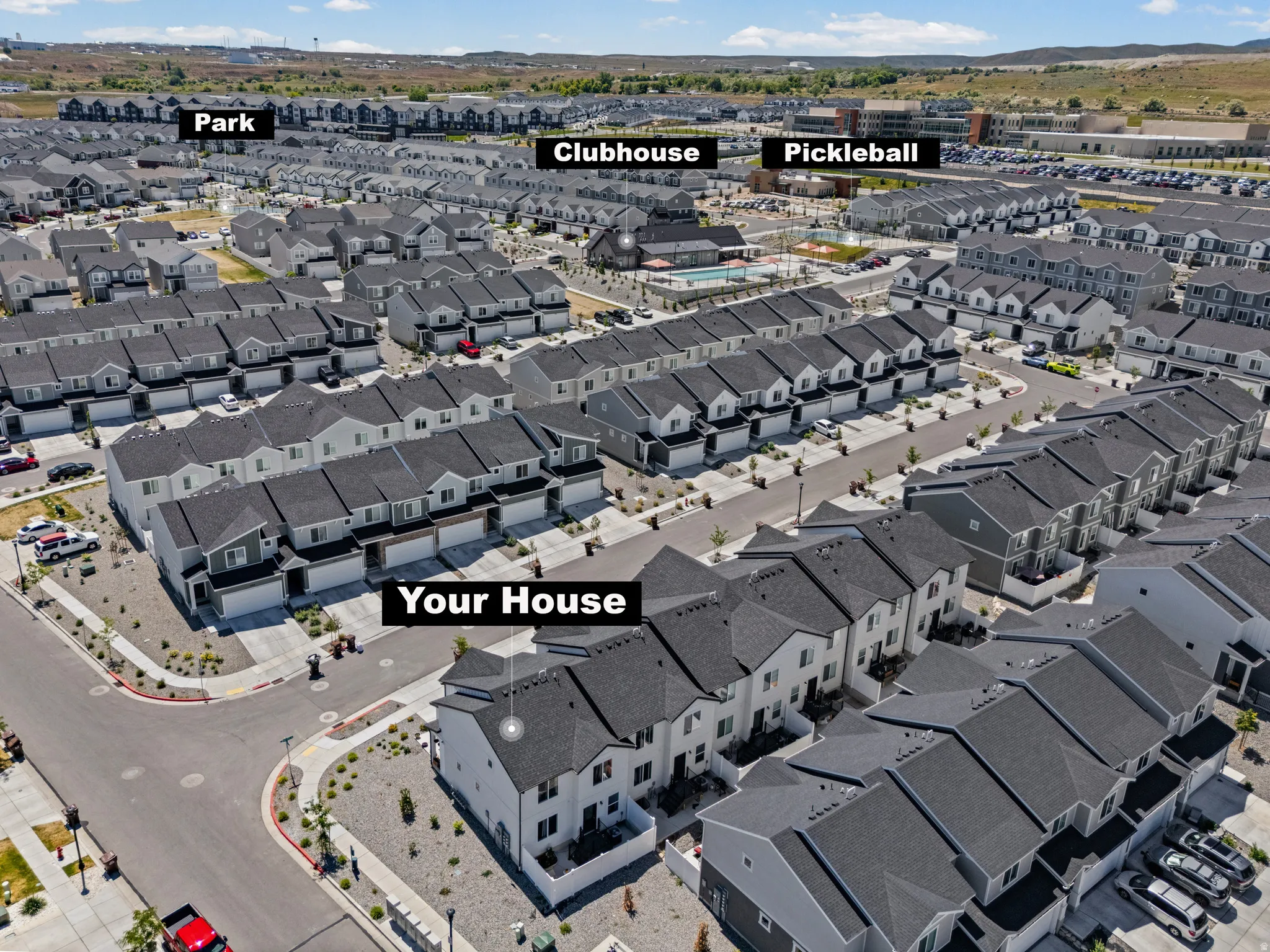 Community aerial featuring multiple residential structures, a central clubhouse, a park area, and pickleball courts