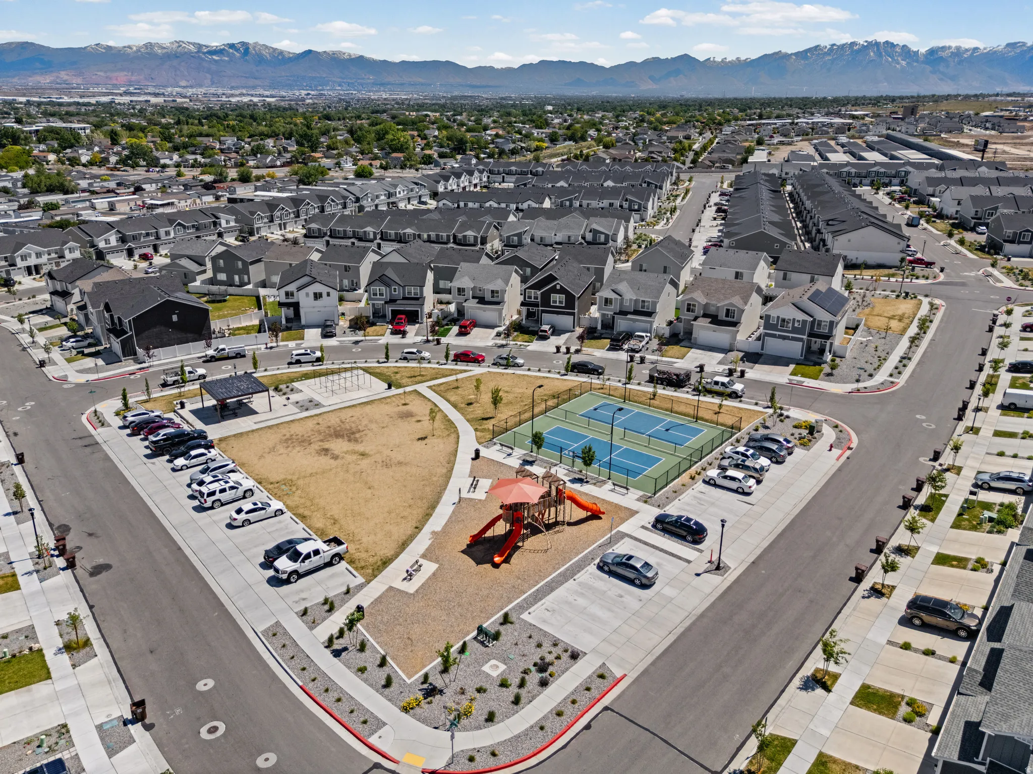Community green space featuring a playground, multi-sport court, and covered seating area