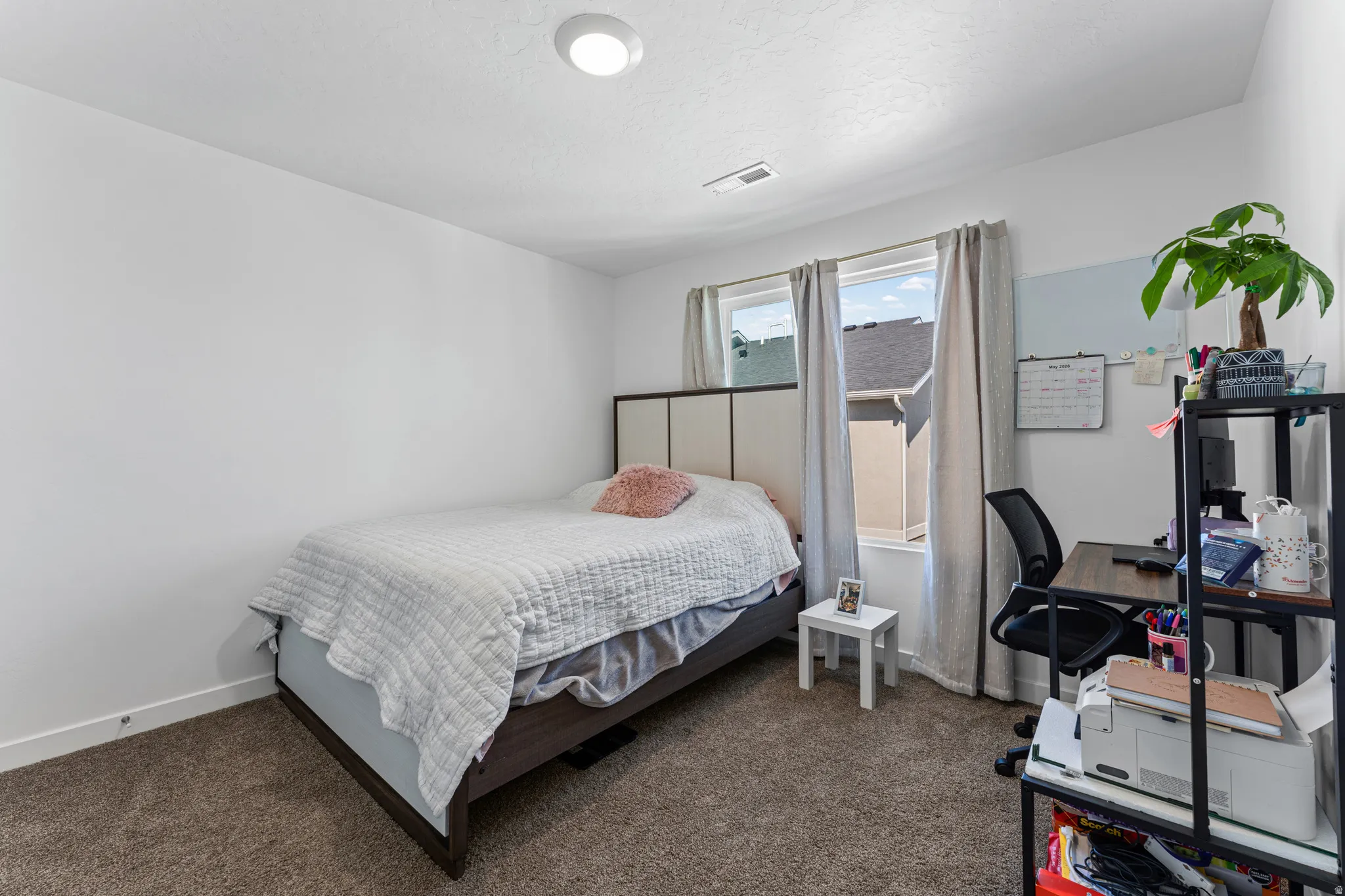 Carpeted room featuring white walls, a single window with curtain rods, and a ceiling-mounted light fixture