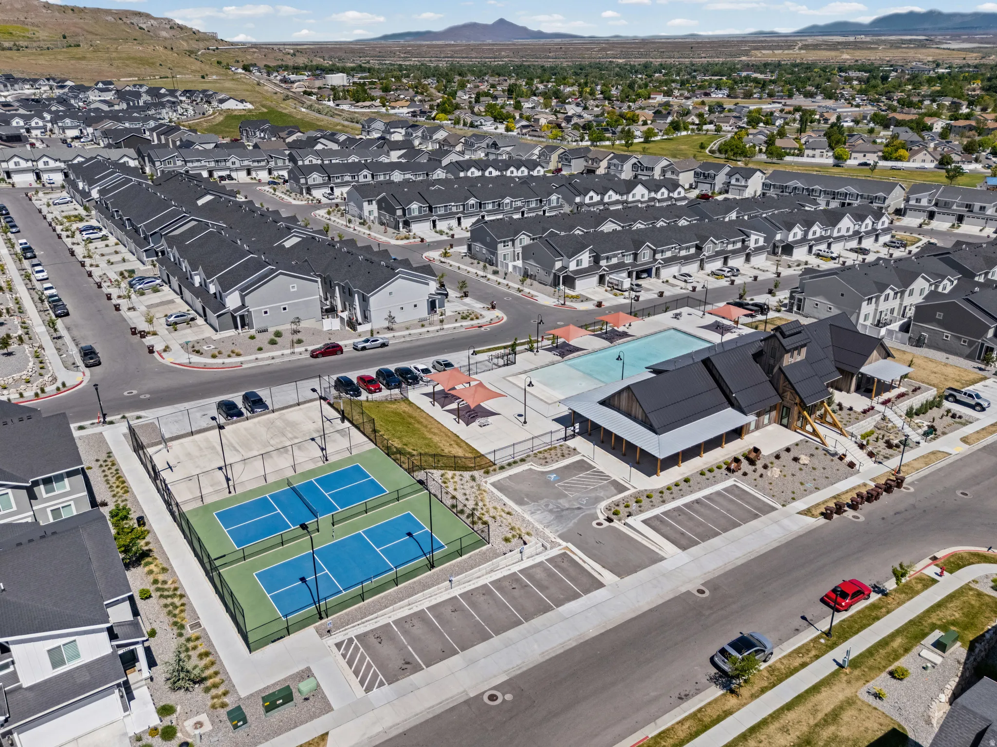 Community amenity center featuring a swimming pool, two pickleball courts, and a clubhouse with dark-pitched roofing