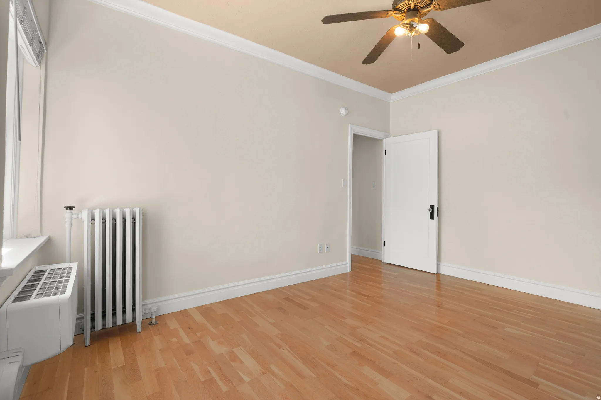 Room featuring wood-finish flooring, neutral wall tones, and white crown molding