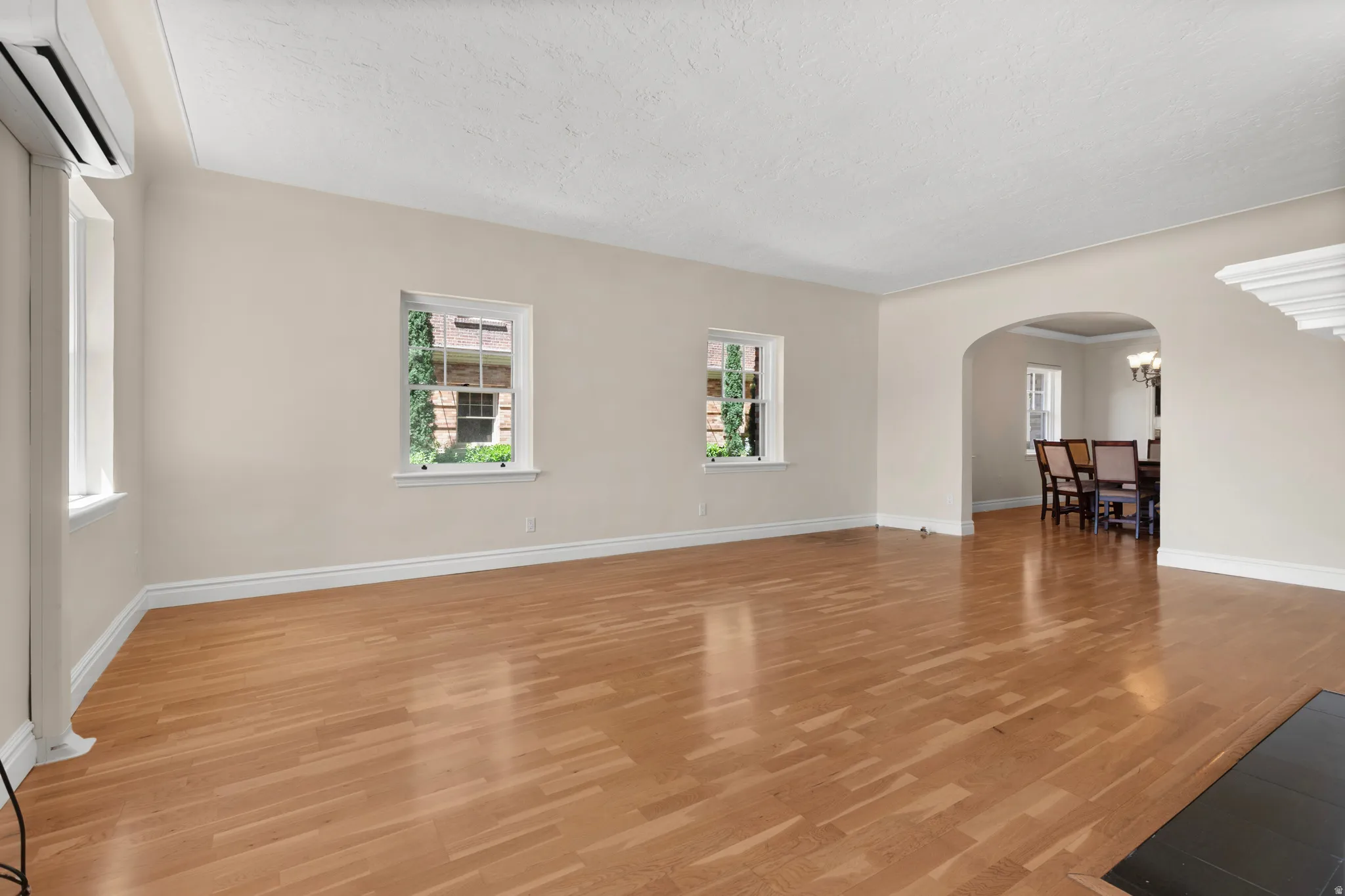 Spacious room featuring wood-finish flooring, light-toned walls, and multiple windows