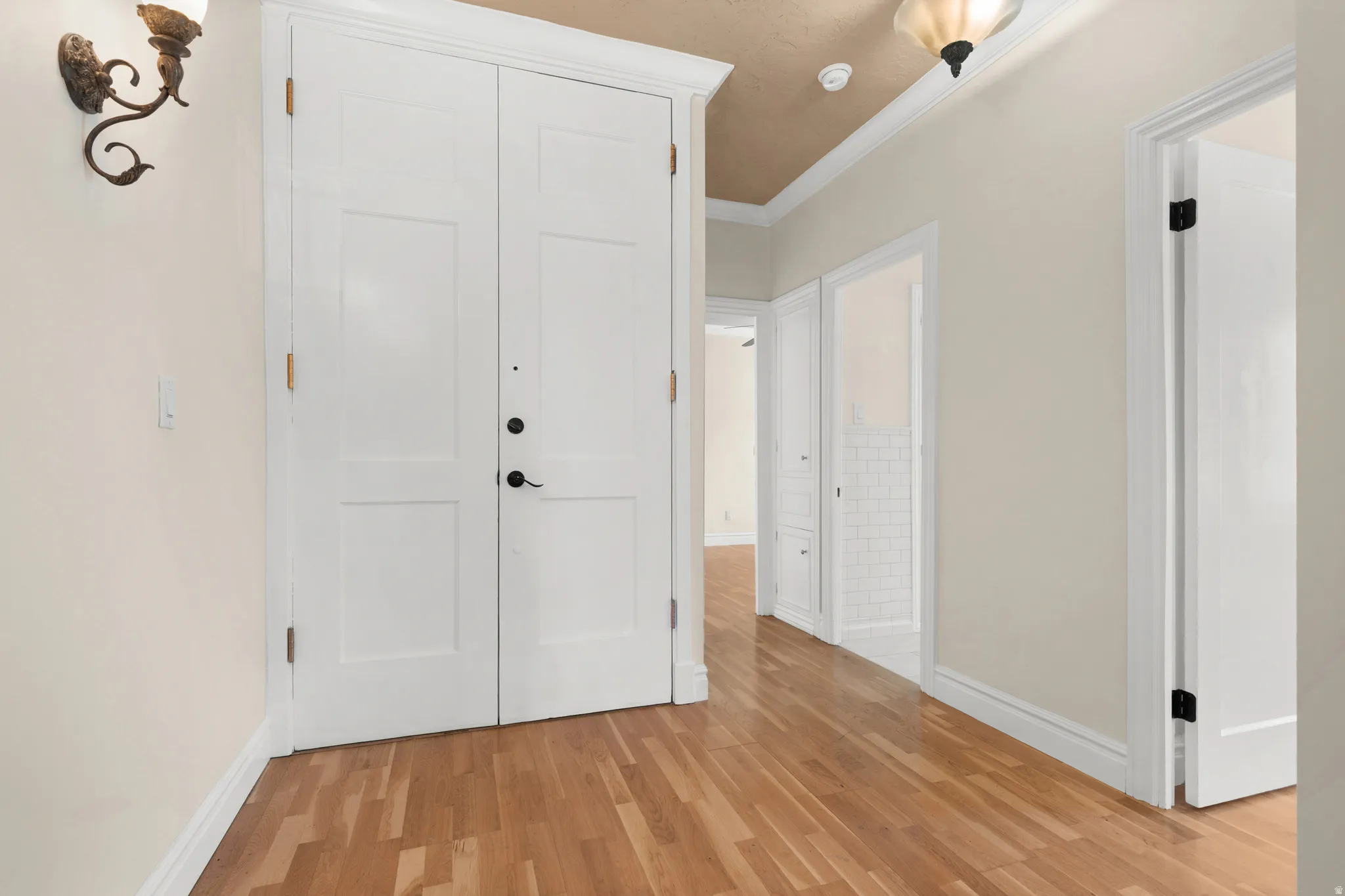 Entryway featuring wood-finish flooring, a double-panel door, and a decorative wall sconce