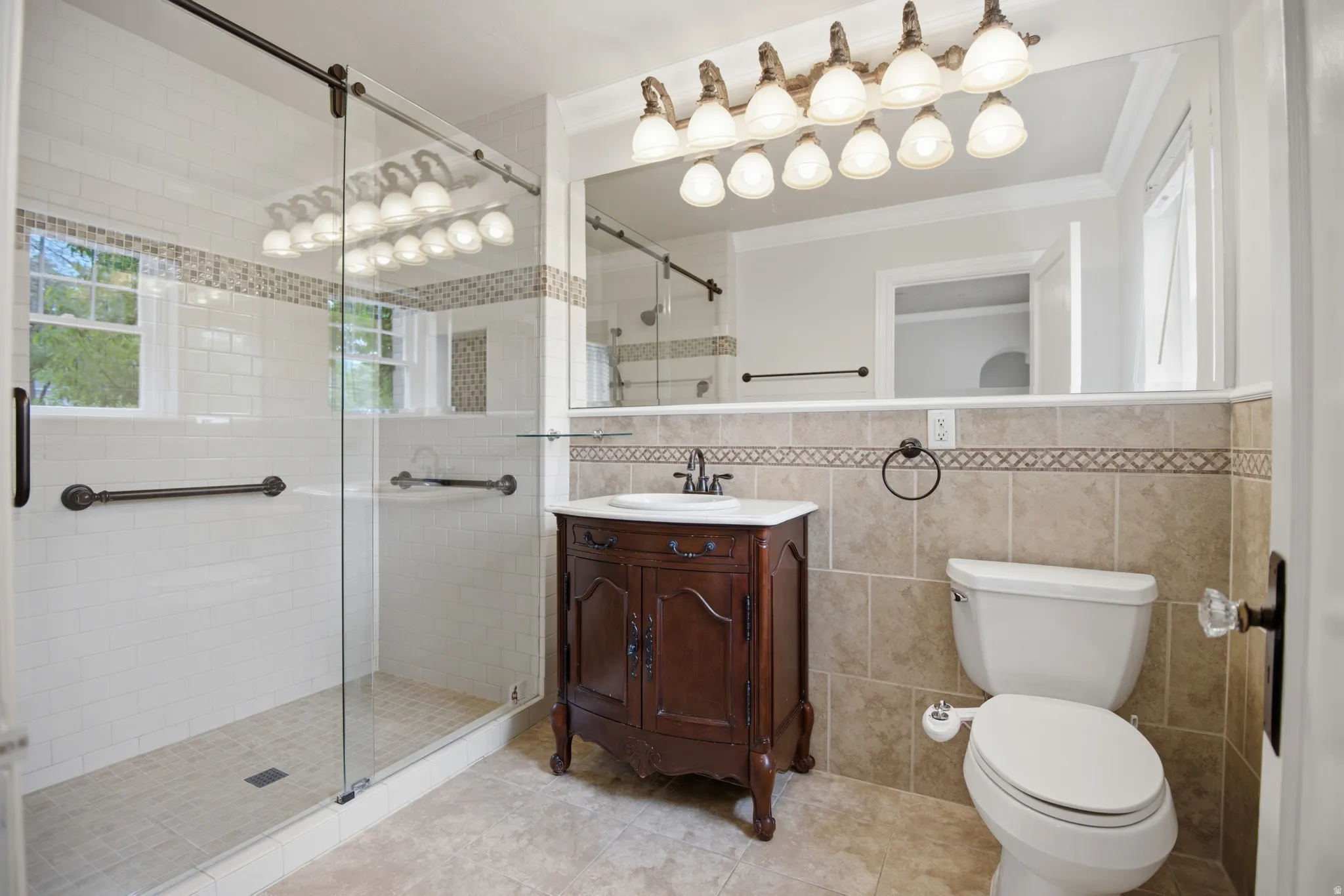 Master bathroom featuring a glass-enclosed shower with white subway tile, a decorative tile accent band, and integrated grab bars