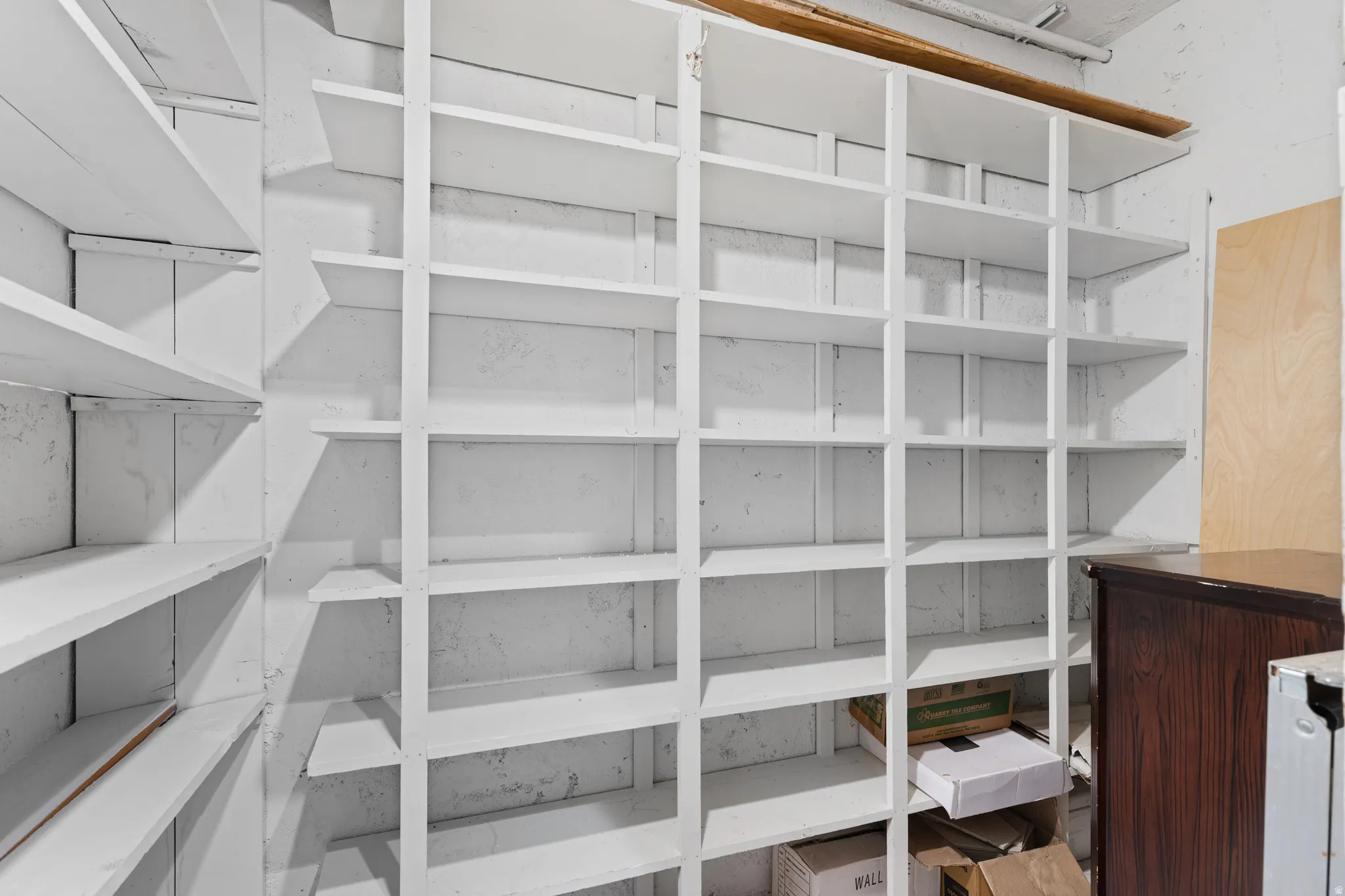 Basement storage closet with built-in white shelving system featuring multiple tiers