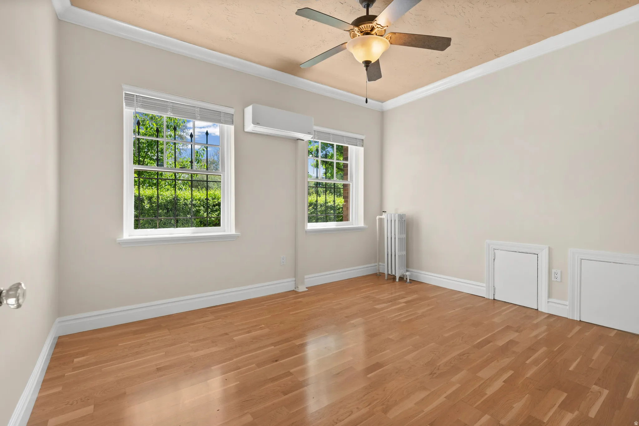 Light wood-finish flooring with white baseboards and crown molding