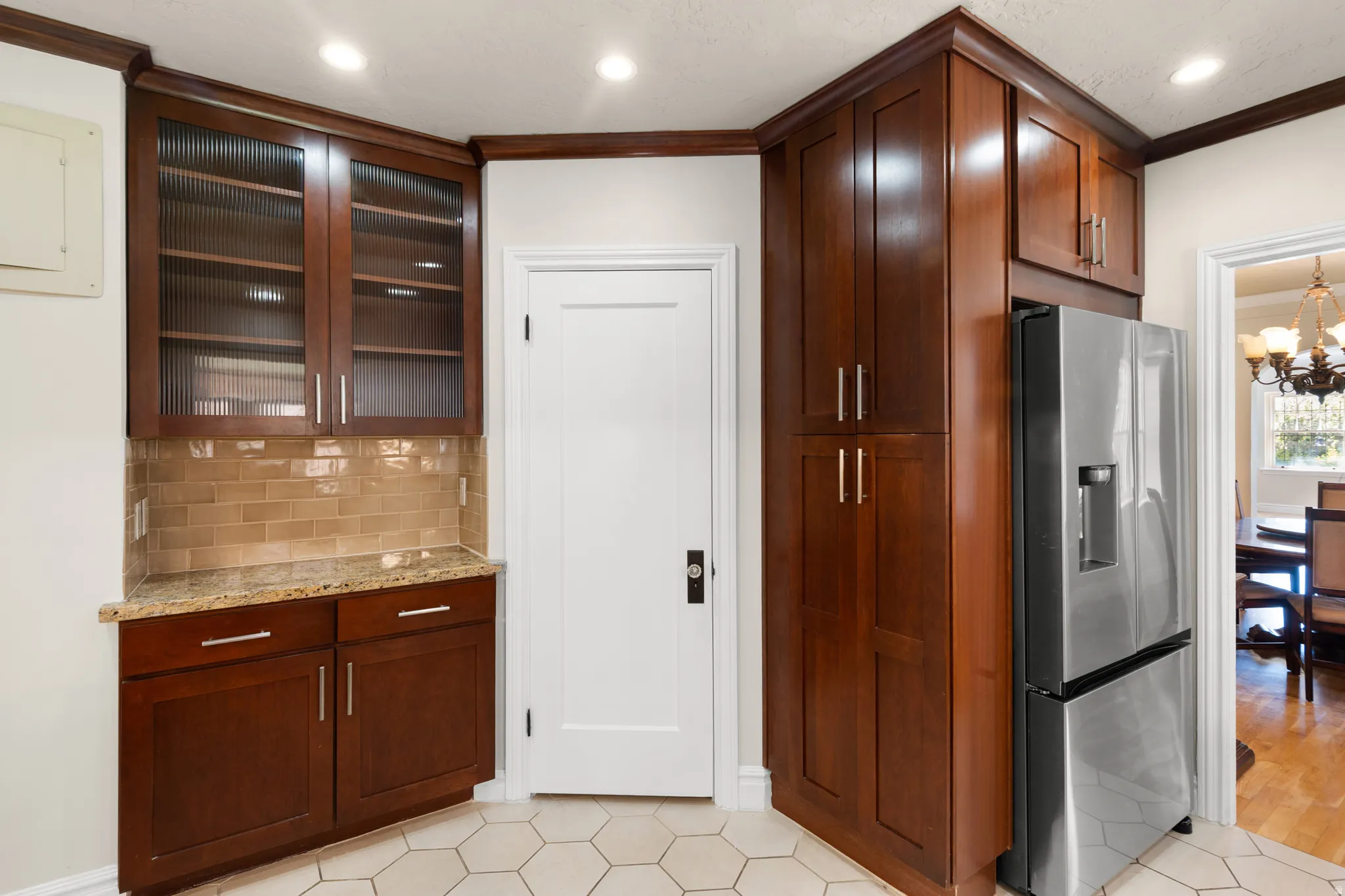 Kitchen featuring rich wood cabinetry, Corner walk in pantry, granite countertops, a subway tile backsplash, and hexagonal floor tiling