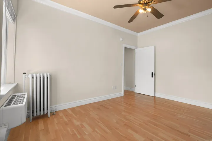 Room featuring wood-finish flooring, neutral wall tones, and white crown molding